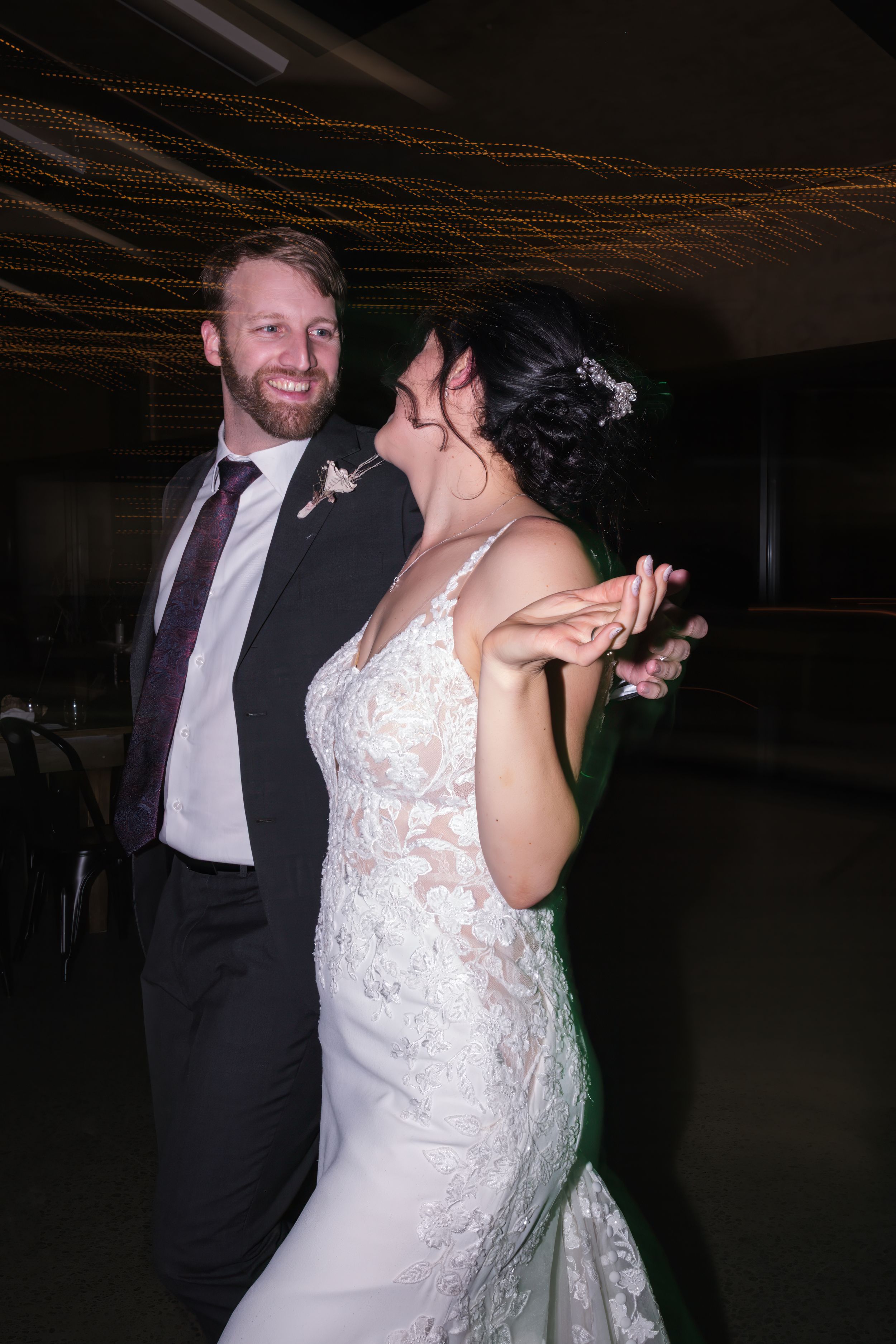 A couple dancing and laughing together at a wedding reception.