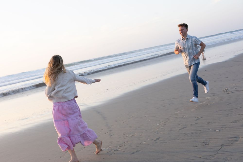Couple running toward each other on a sandy beach at sunset.
