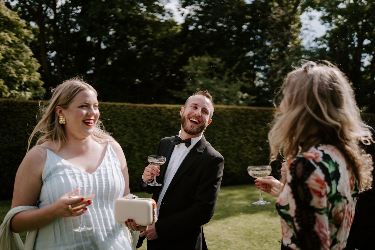 wedding guests laughing with glasses of champagne in their hands at dewsall court in herefordshire