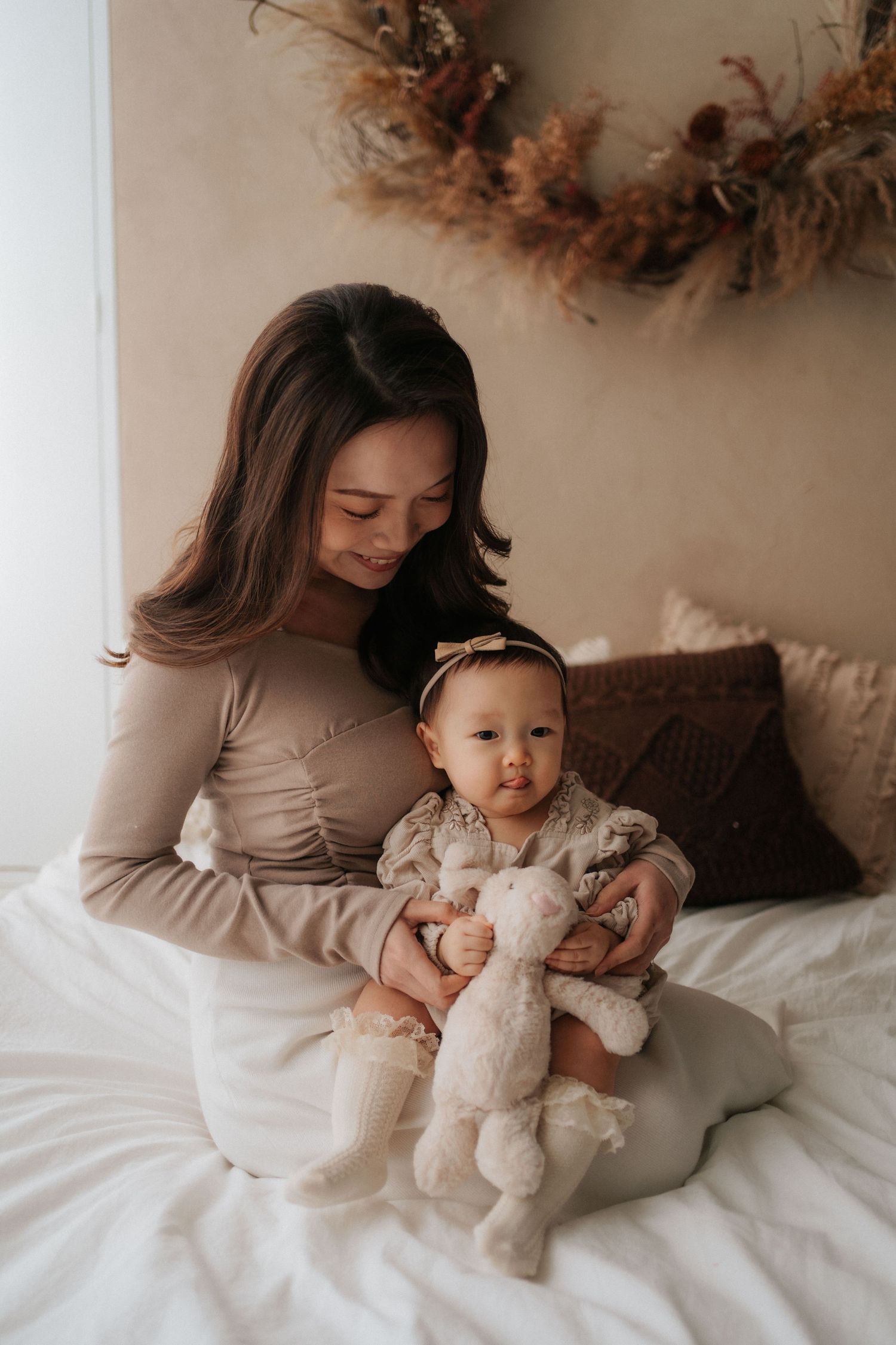 A parent and baby share tender moments together on white bedding in a series of intimate lifestyle photographs.