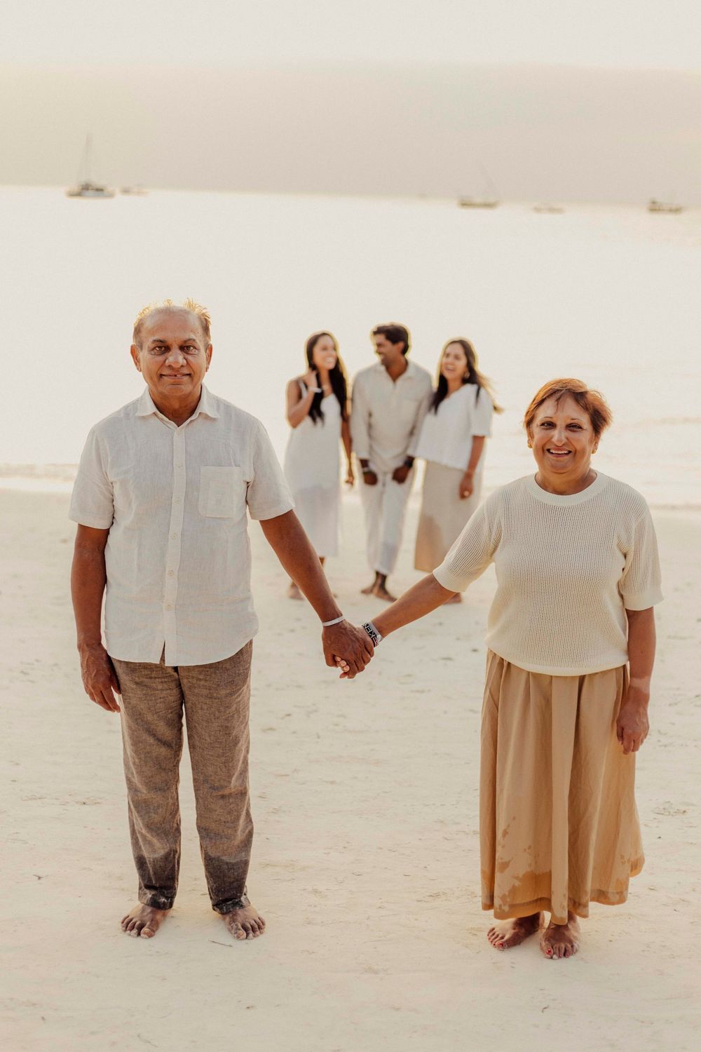 Indian couple walking barefoot on Zanzibar beach