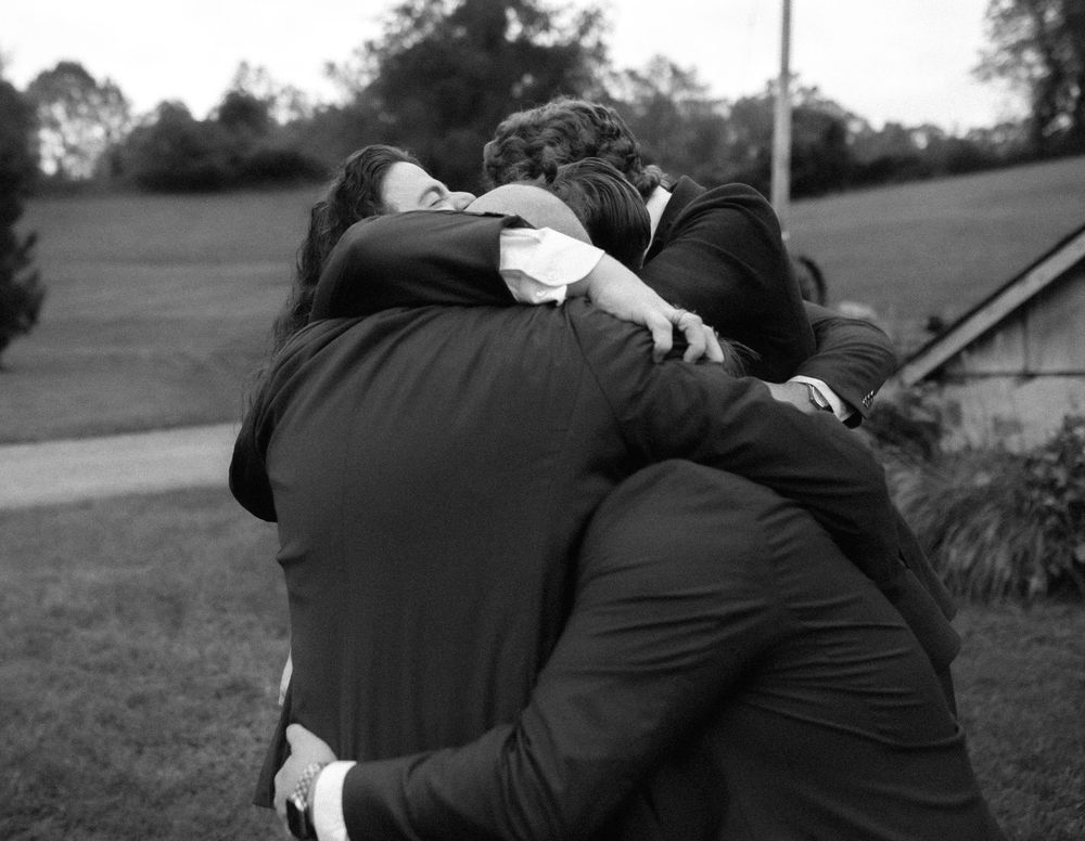 A black and white sequence showing an emotional embrace between wedding guests.