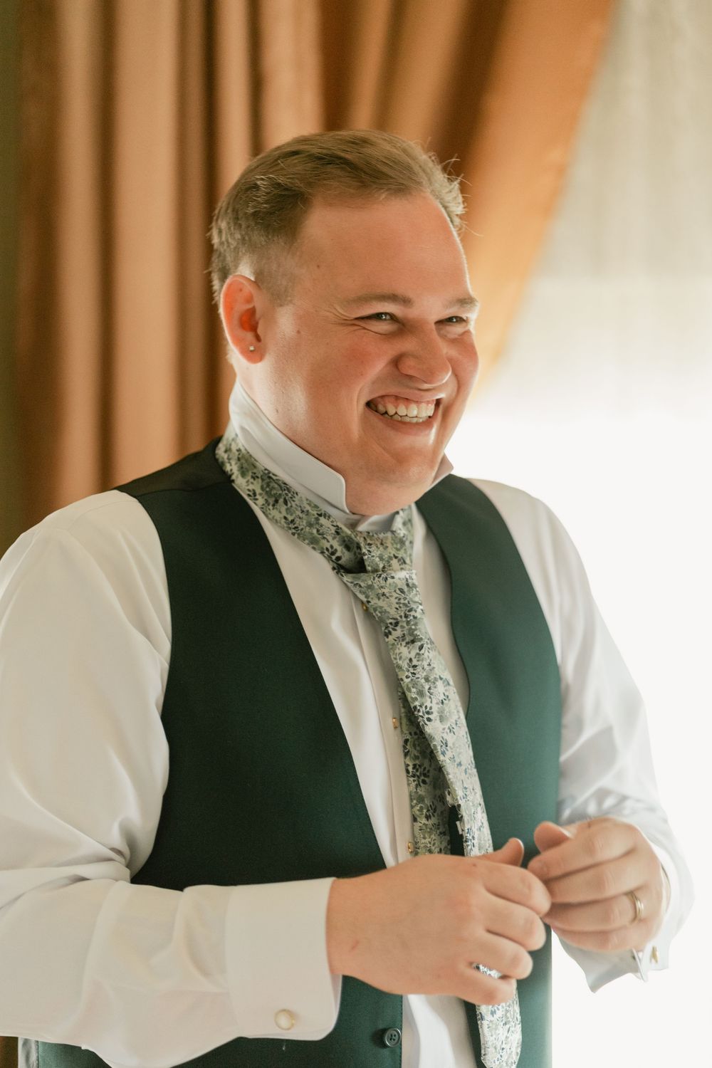 Person in formal attire adjusts their tie while getting ready for a special event.