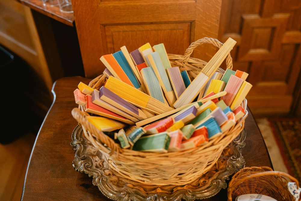 Colorful chalk sticks and art supplies arranged in a woven wicker basket on wooden table.