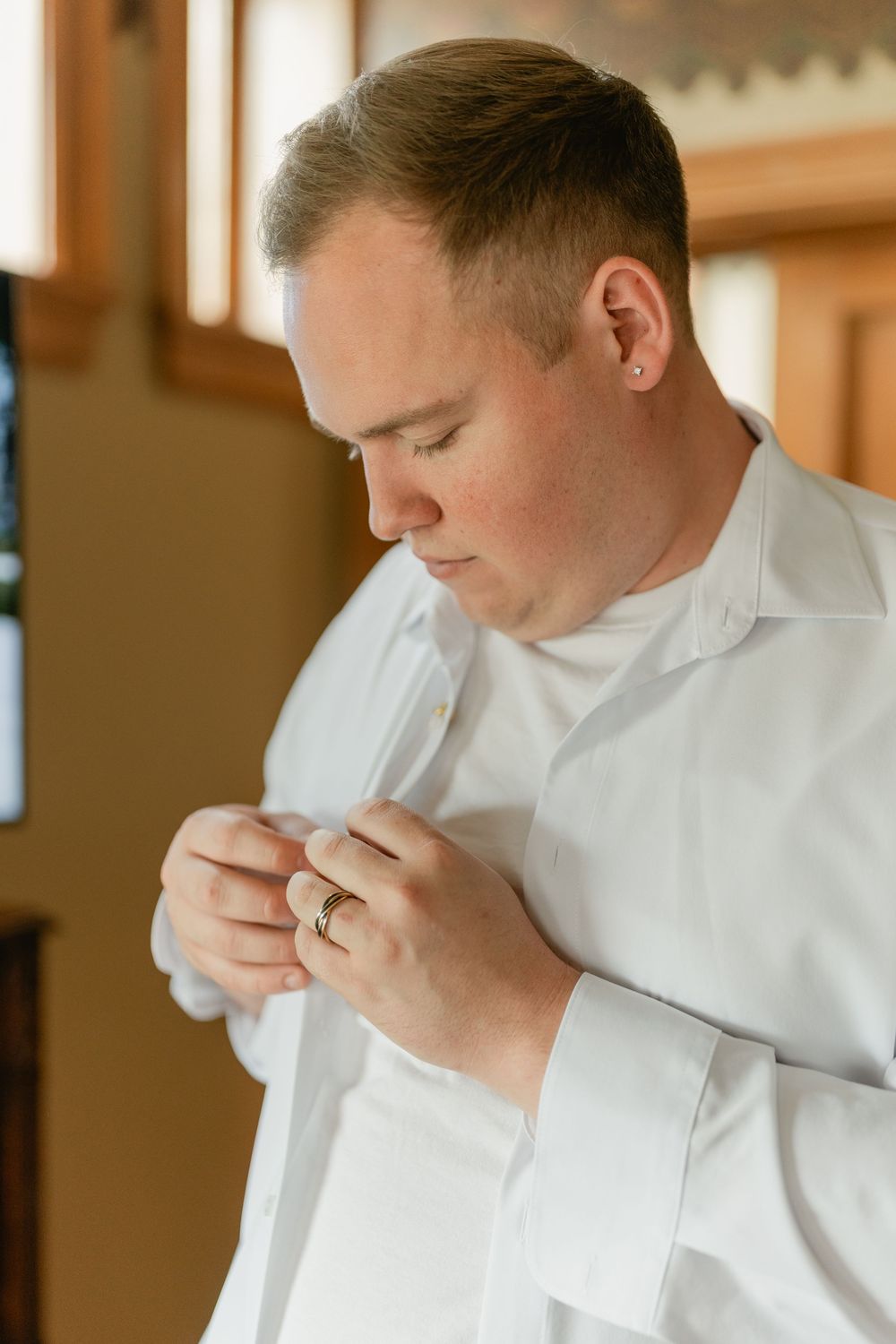 Person in white dress shirt adjusts buttons while getting ready.