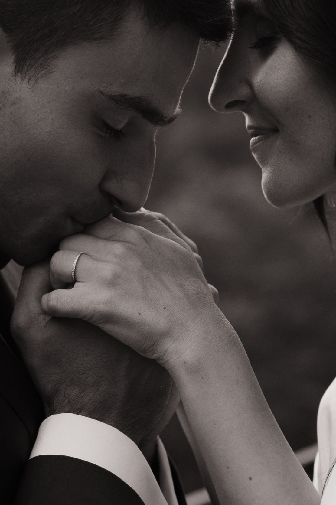Deux jeunes mariés sont de profils et l'homme tiens les mains de sa femme pour les embrasser.