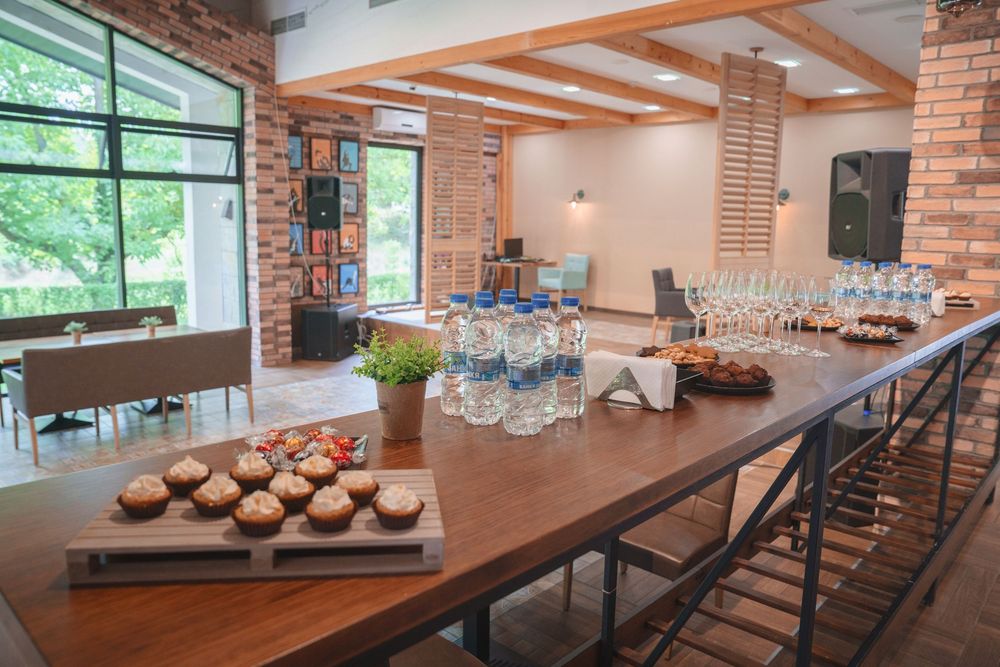 Modern industrial event space with exposed brick walls, wooden beams, and multiple seating areas for gatherings.