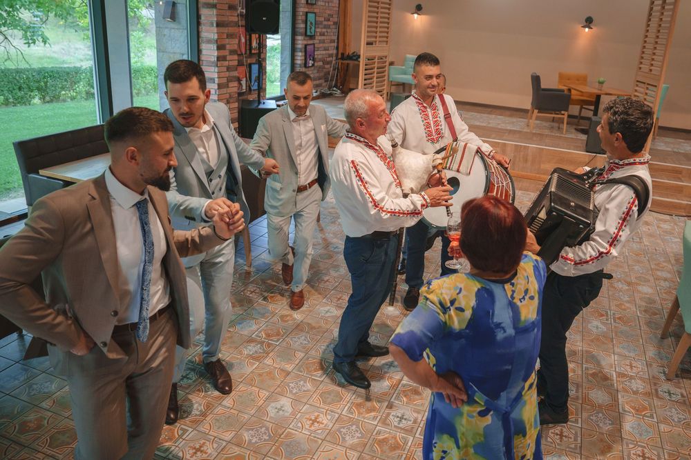 A group of guests in formal attire gather and socialize in a modern indoor venue with brick flooring.