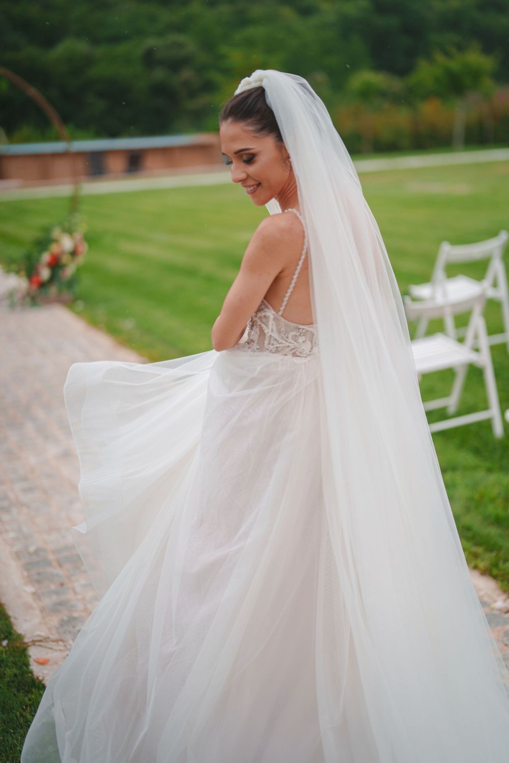 Ethereal wedding dress with flowing tulle veil captured in romantic outdoor garden setting.