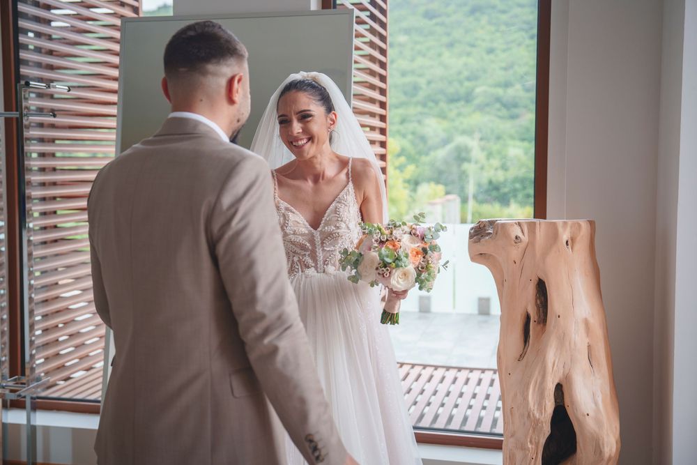 A couple shares their first look moment during a wedding ceremony on a rustic porch overlooking mountains.