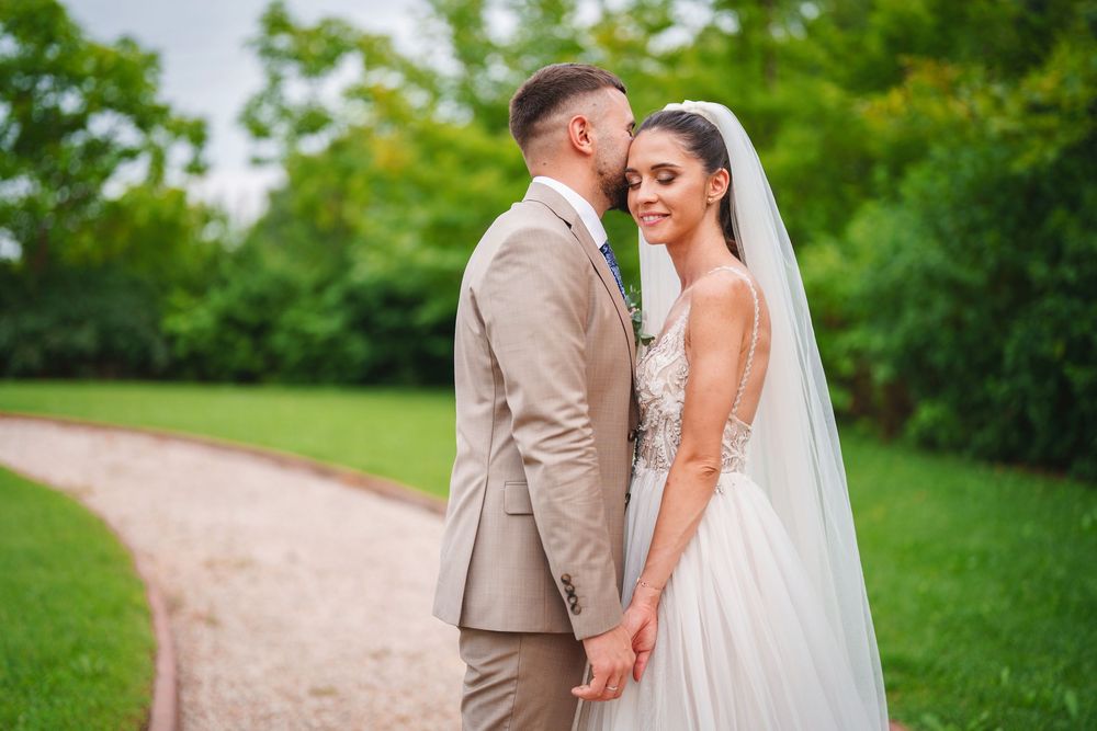 Romantic wedding couple walking along a gravel path surrounded by lush greenery.