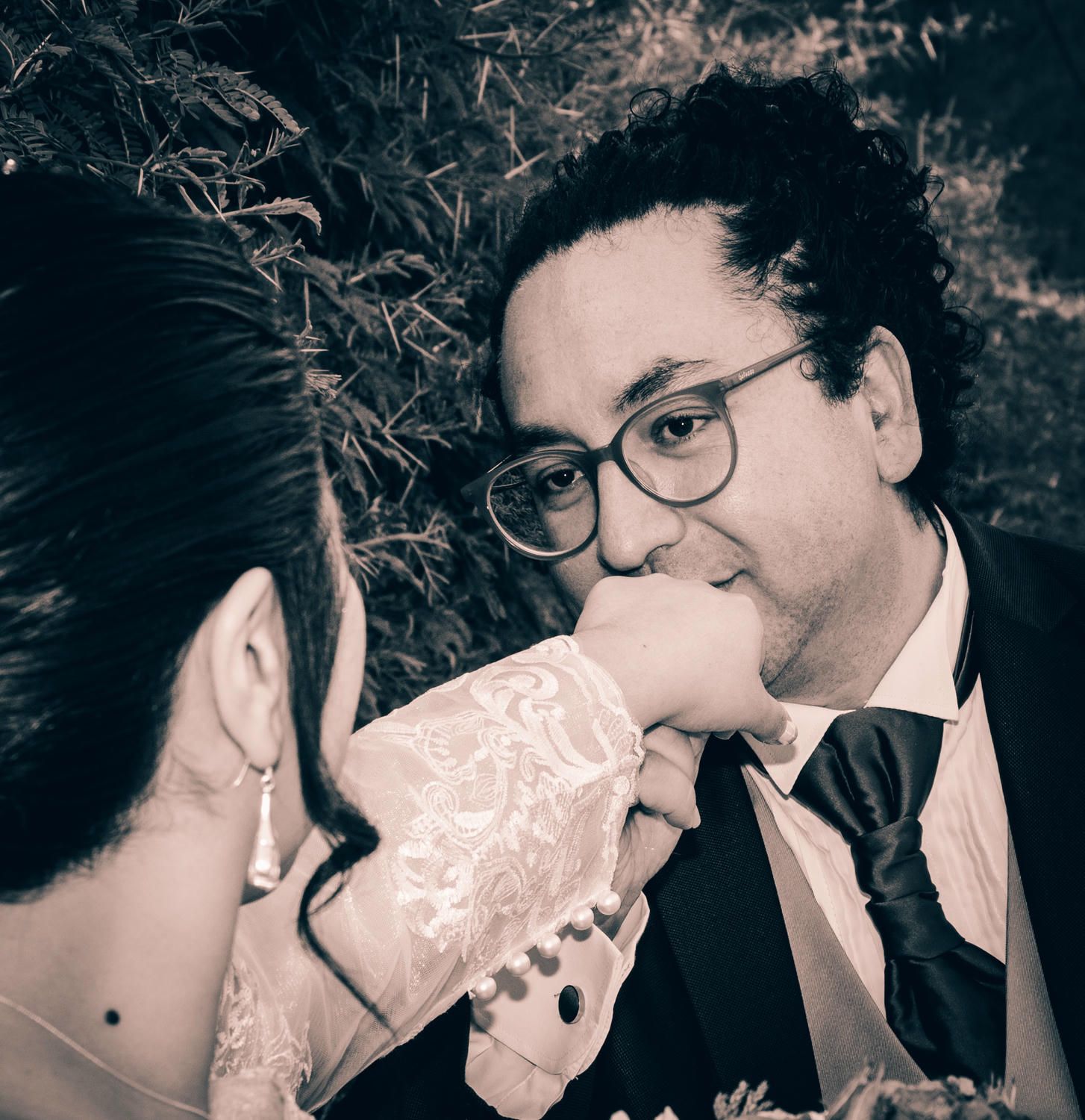 matrimonio posando junto a autos vintage con montañas al fondo.