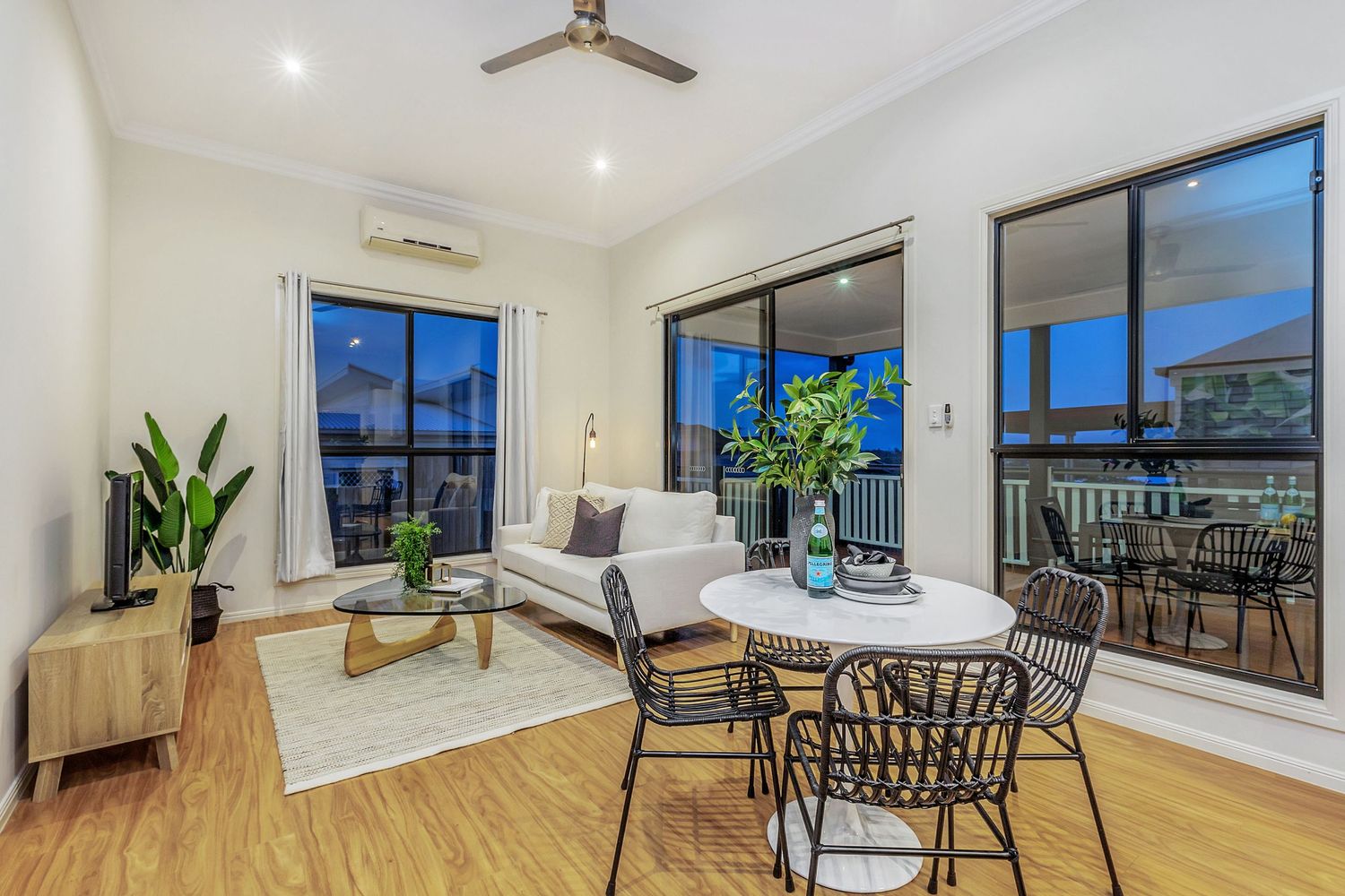 Bright open-plan living and dining area with timber floors and balcony access.