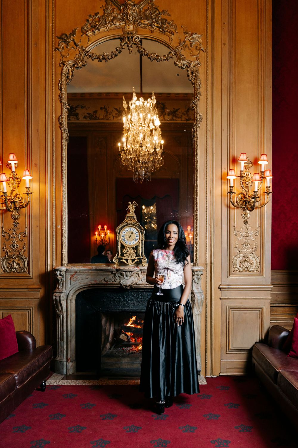 A gothic scene with crystal chandeliers and ornate wall panels in a luxurious room with red carpeting.