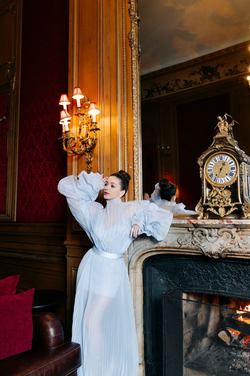A dramatic scene in a vintage room with ornate decor, featuring white flowing fabric against dark walls.