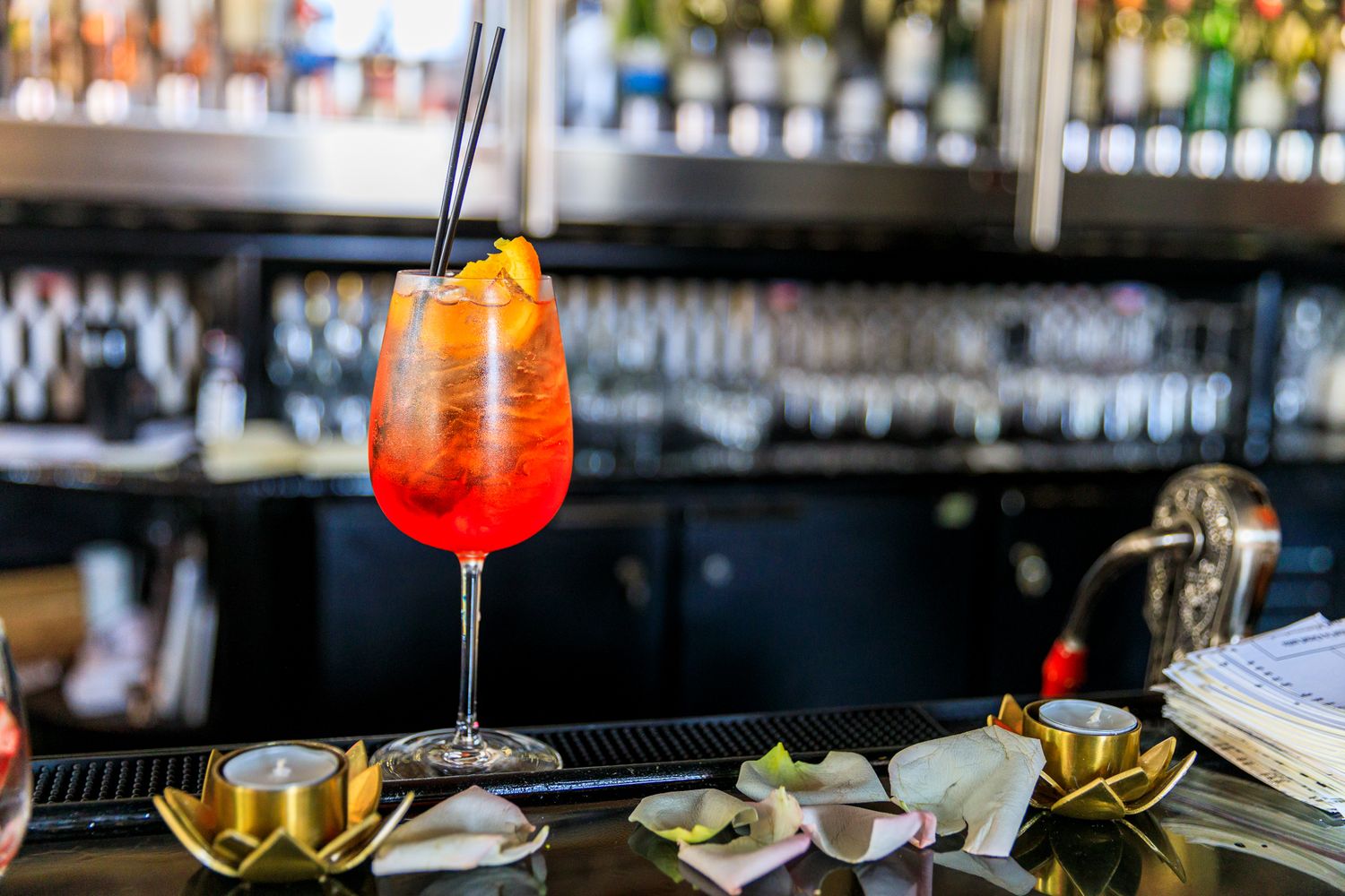 Colorful cocktails and drinks lined up on a sleek modern bar counter with bottles displayed in the background. live event photography stl