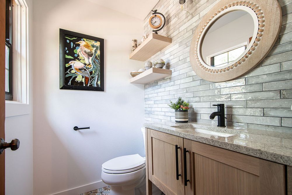 Rustic-modern bathroom design with a floor-to-ceiling stone accent wall and circular decorative mirror.