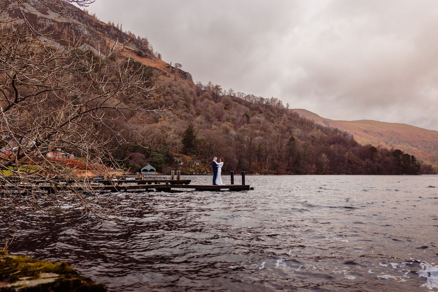 Couple embrace at Inn on the Lake jetty on a cloudy autumn day.