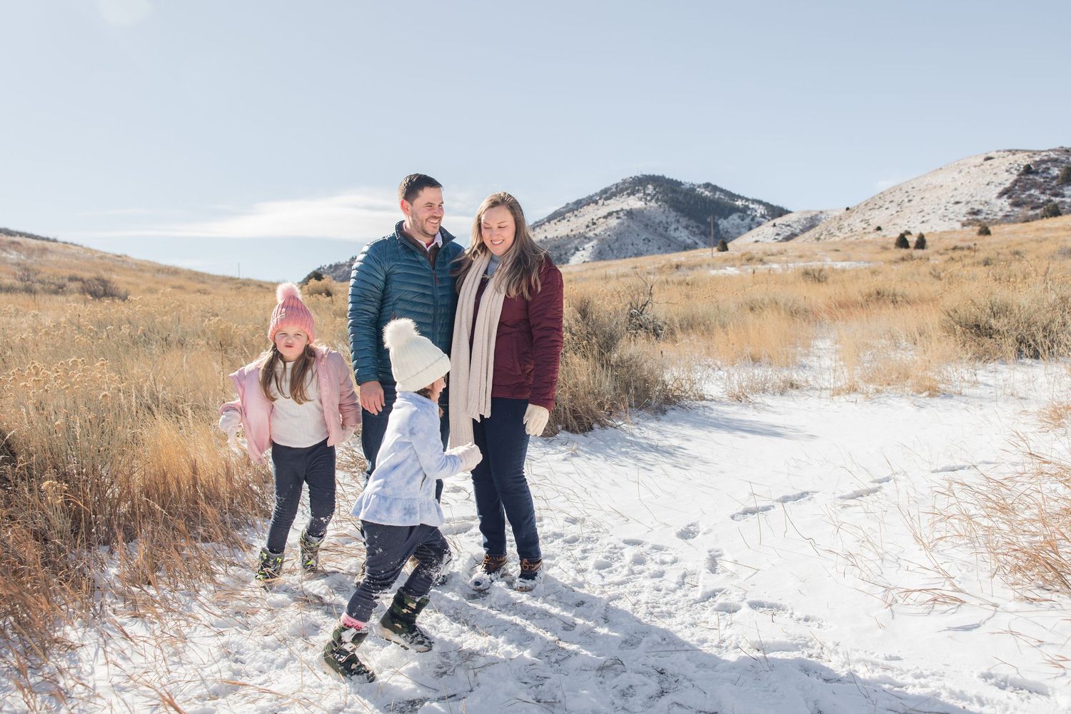 A group poses together in a snowy winter landscape with mountains and dry grass in the background.