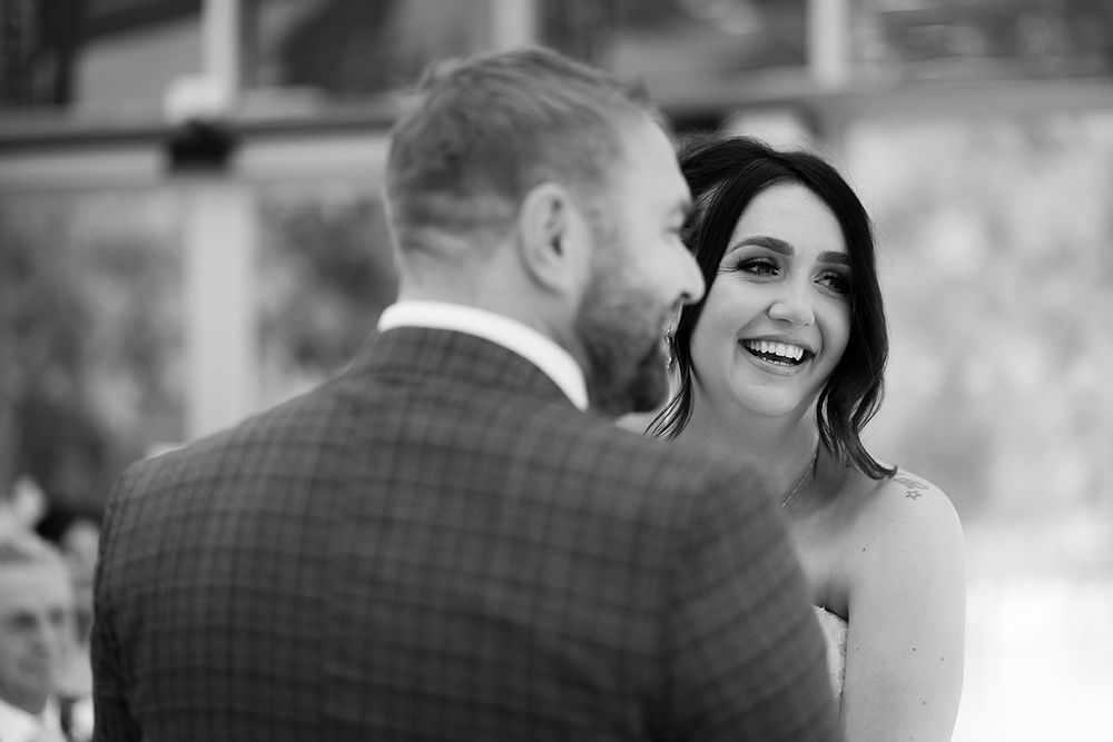 A happy couple shares a joyful moment together during their wedding celebration in black and white photography.