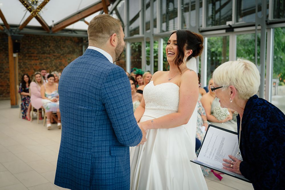 Guests mingle during a wedding reception in an elegant indoor venue with natural lighting.