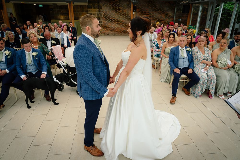 Newlyweds perform their first dance surrounded by guests at an elegant indoor wedding reception.