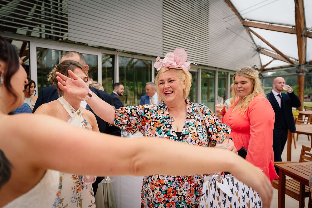 A candid moment of laughter and celebration at an outdoor wedding reception with guests in colorful attire.
