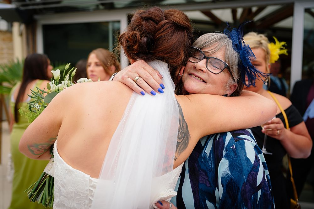 A collection of wedding photos showing guests hugging and embracing during an outdoor celebration.