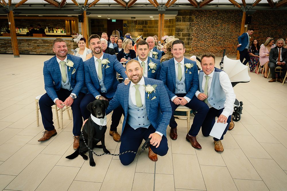 Groomsmen in blue suits sitting on steps showing off their colorful patterned socks in a fun wedding photo.