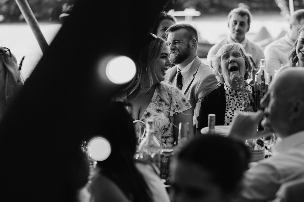 Black and white photo of wedding guests reacting emotionally during reception speeches.