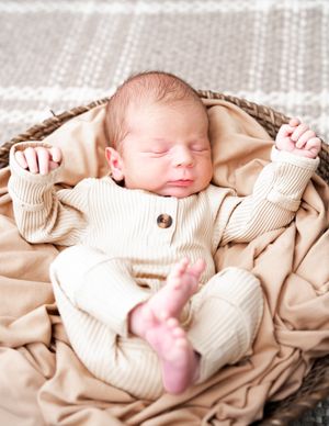A sleeping newborn in a cream knit sweater lies peacefully on beige fabric in a series of connected photos.