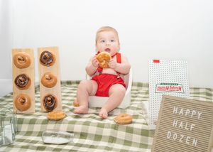 A collage of baby photos with donuts and Halloween themed decorations arranged in a horizontal strip.