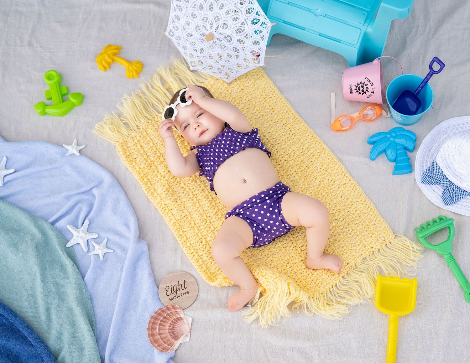 Flat lay of baby toys, blankets, and accessories in pastel colors arranged on white background.