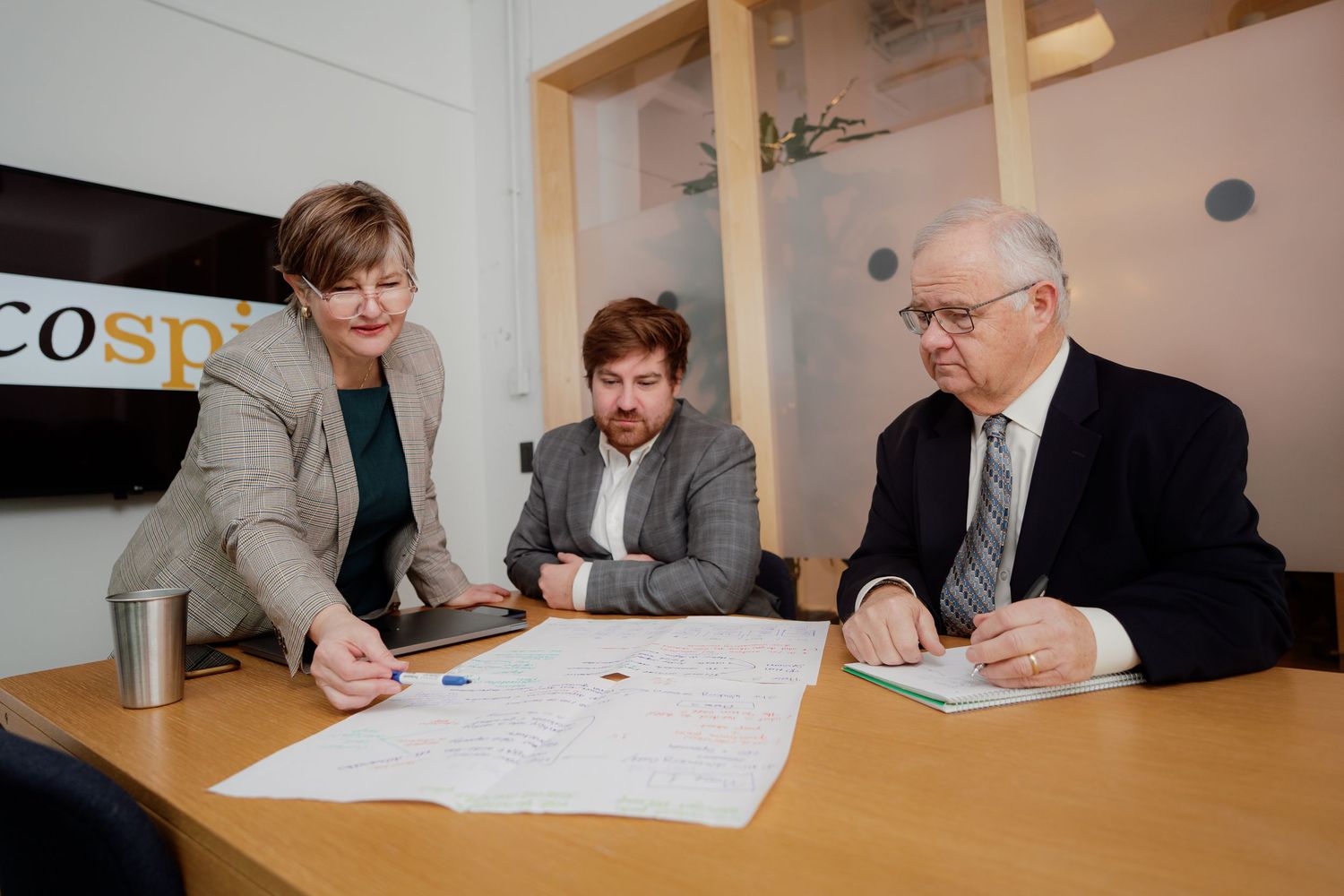 Business professionals review documents and collaborate at a conference table in an office setting.