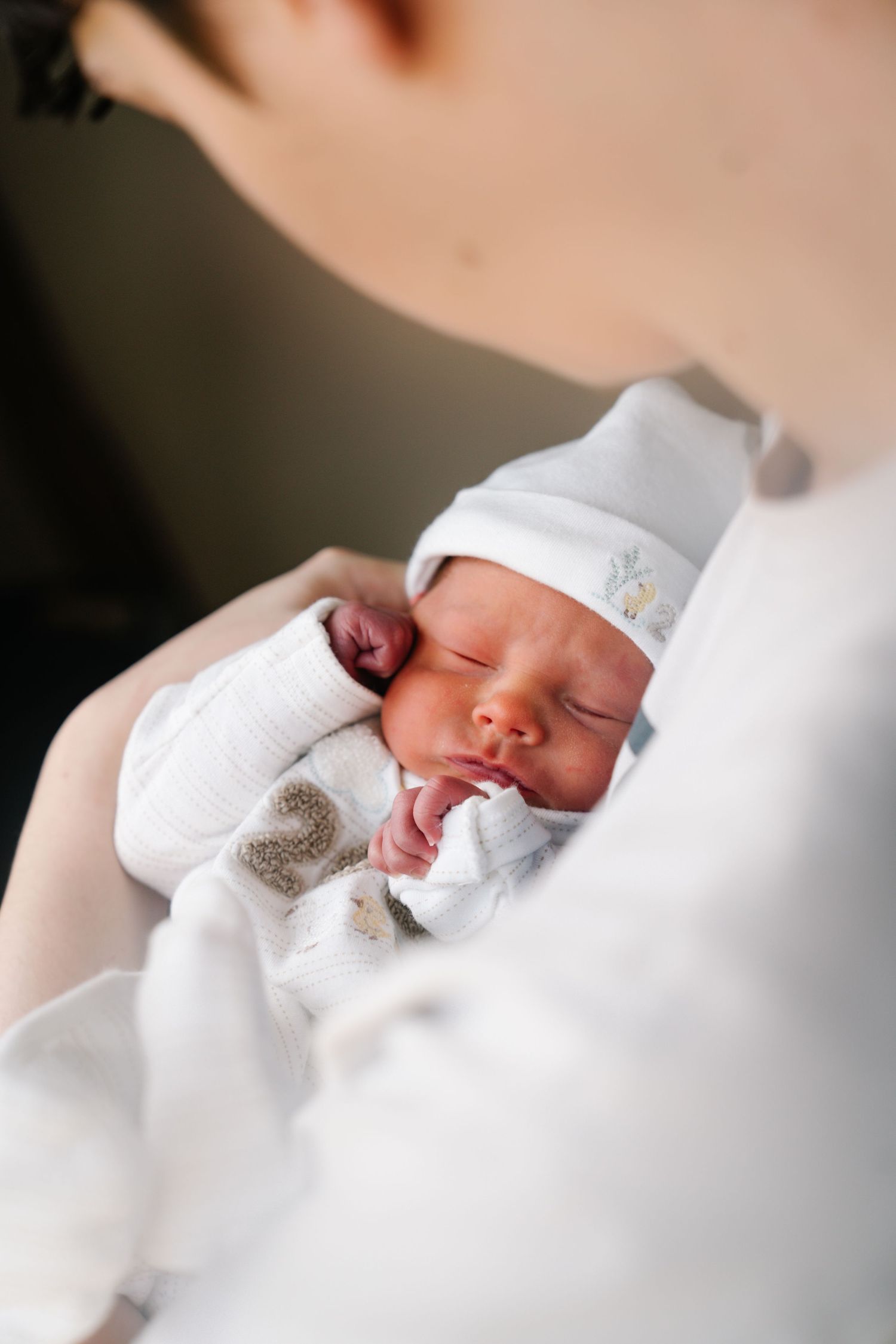 A newborn baby swaddled in white blankets rests peacefully in a series of connected photos showing different angles.
