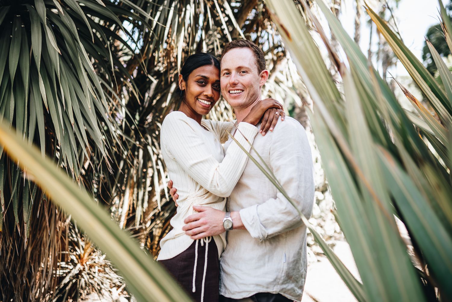 A couple shares intimate moments among tropical plants during an outdoor photo session in Melbourne