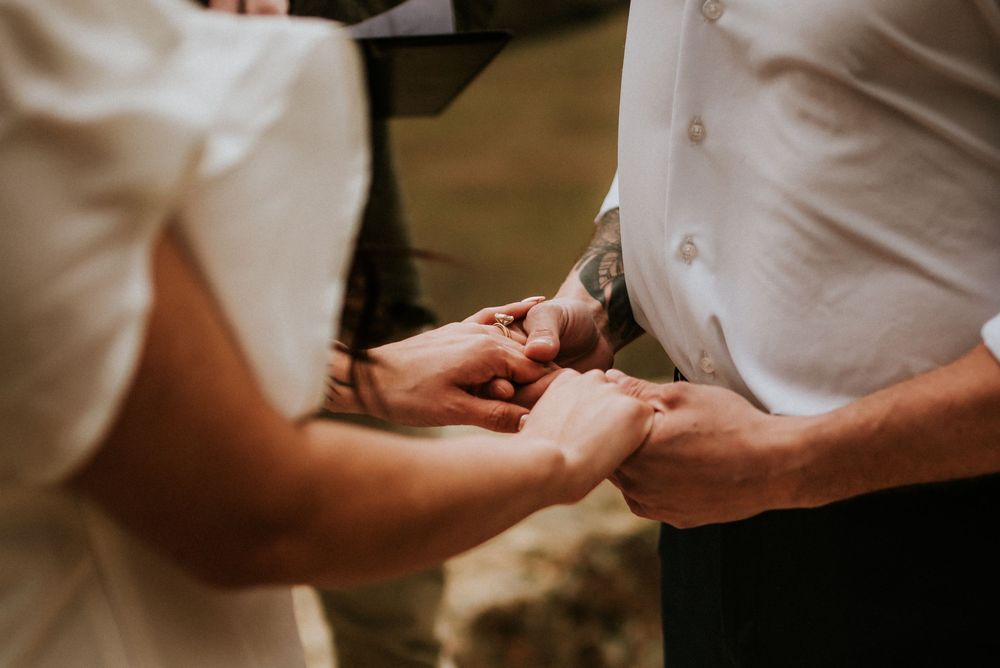 Elopement couple holding hands during the vows of a ceremony while affordable photographer takes a detailed photo of their hands in TN.