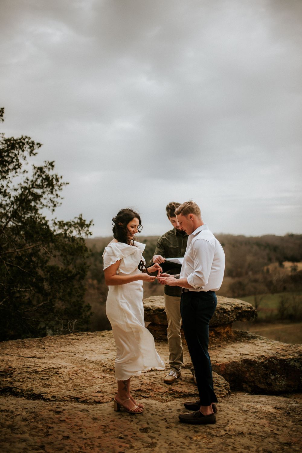 Elopement couple and their officiant at the peak of a hike exchanging vows while affordable photographer takes a photo in Tennessee.
