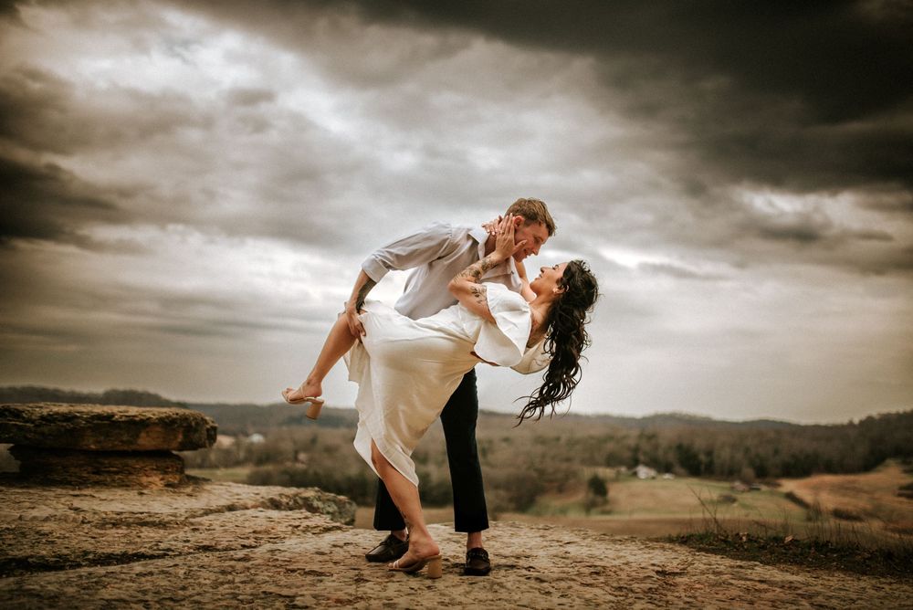 Dramatic skies while a husband dips his wife during bridal couple portraits after their elopement ceremony in Tennessee.
