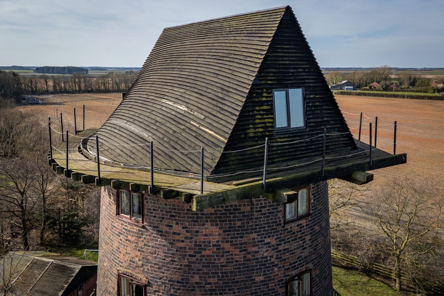 Close view of restored windmill tower and balcony at Windmill Farm Burscough with farmland stretching beyond