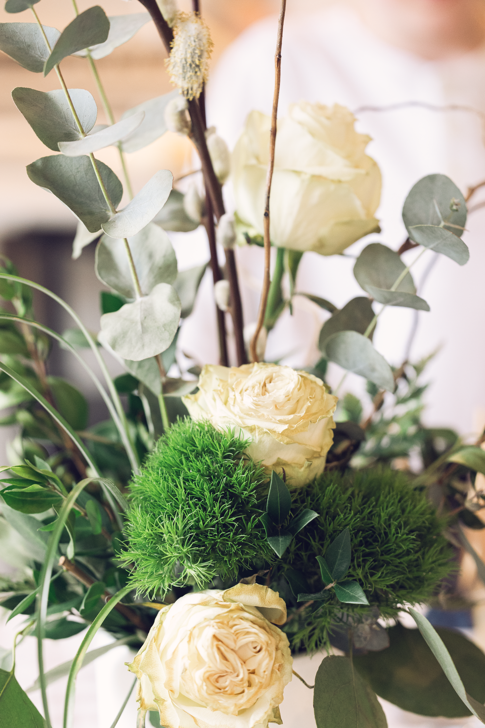 Elegant bouquet of white roses, eucalyptus leaves, and green moss balls in a floral arrangement.