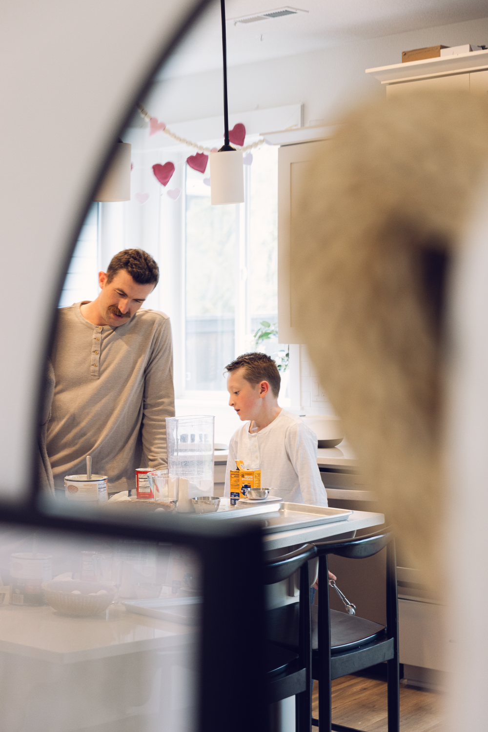 Father and son baking in a bright kitchen decorated with heart garland for Valentines Day.
