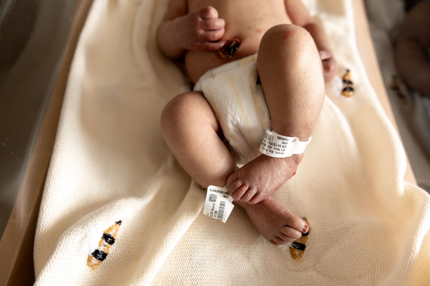Newborn baby's tiny feet in a hospital bassinet in Central Indiana with identification bracelet during a Fresh 48 session in