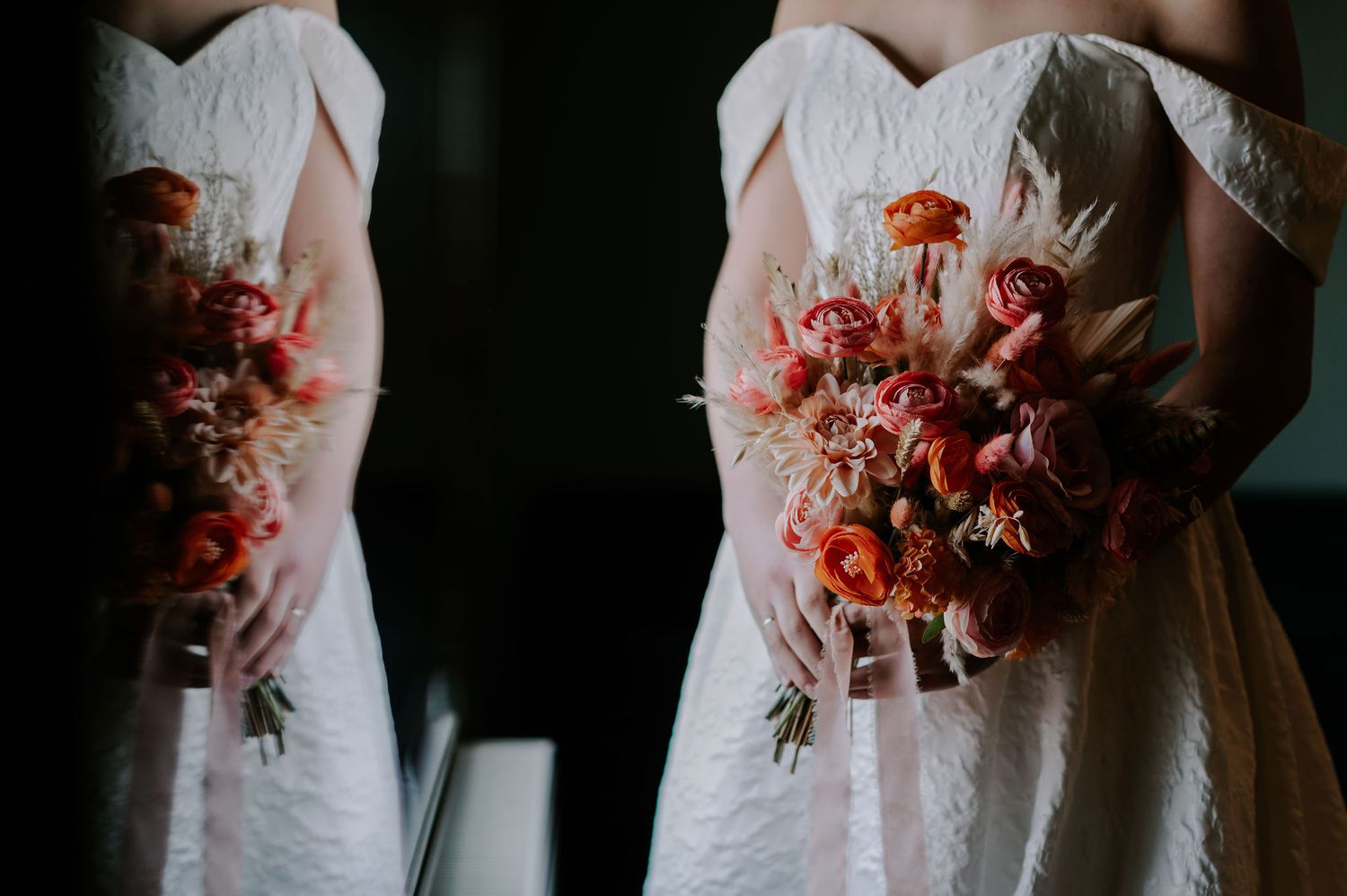 Orange and pink flower bouquet being held by a bride as she stands by a window.