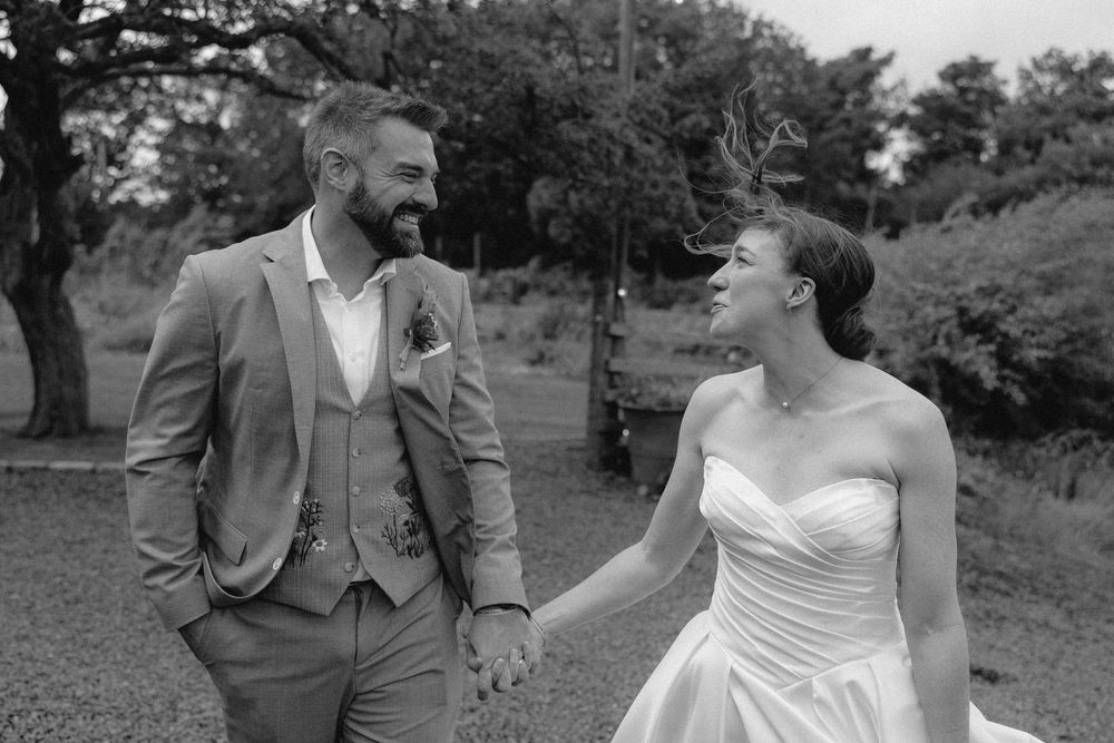 A series of candid wedding moments captured in black and white showing laughter and joy in a natural setting.