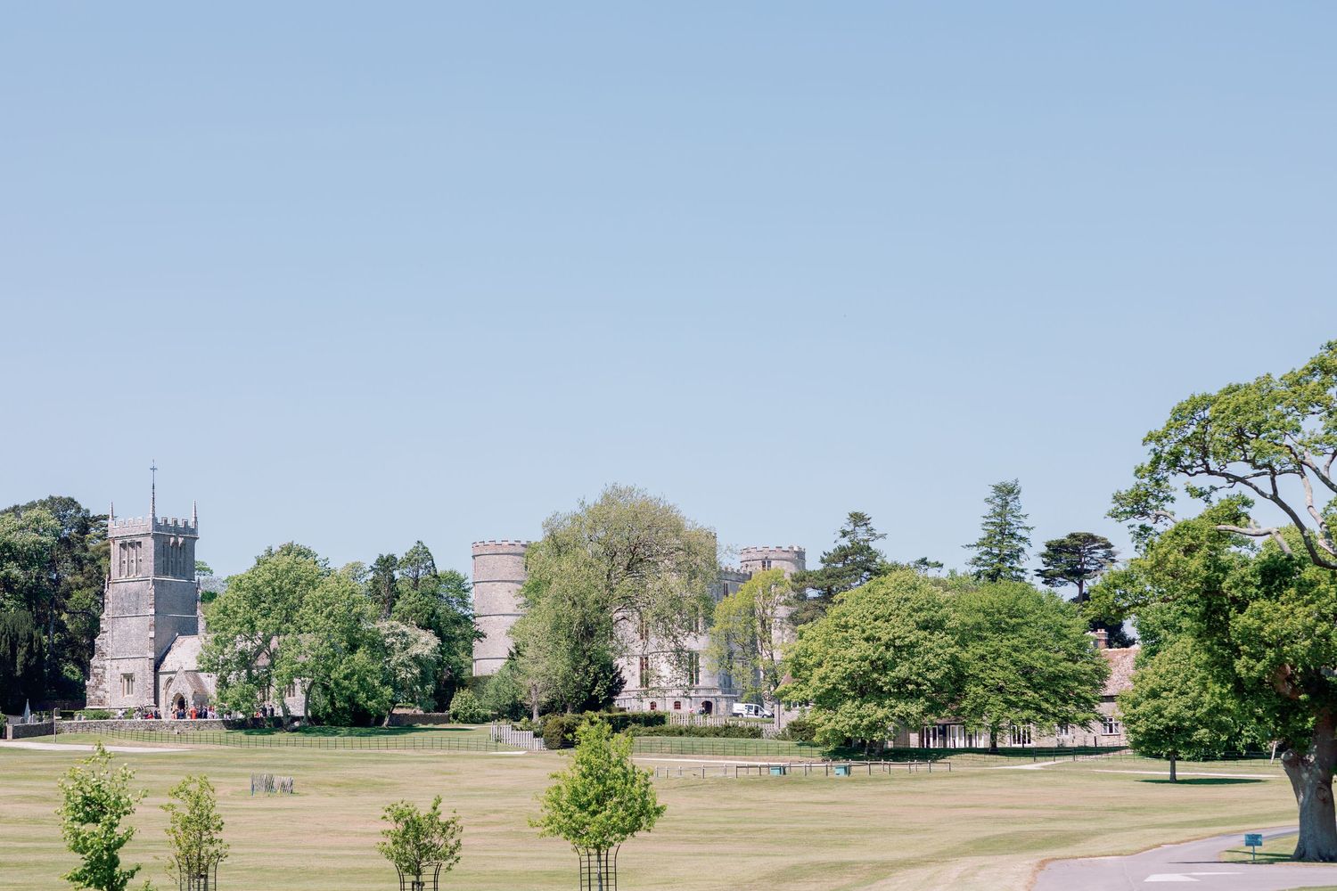 A panoramic view of a grassy landscape with trees and buildings scattered across rolling hills in the distance.