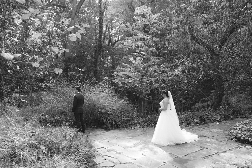 A black and white trail camera sequence shows a deer walking through a wooded path at night.