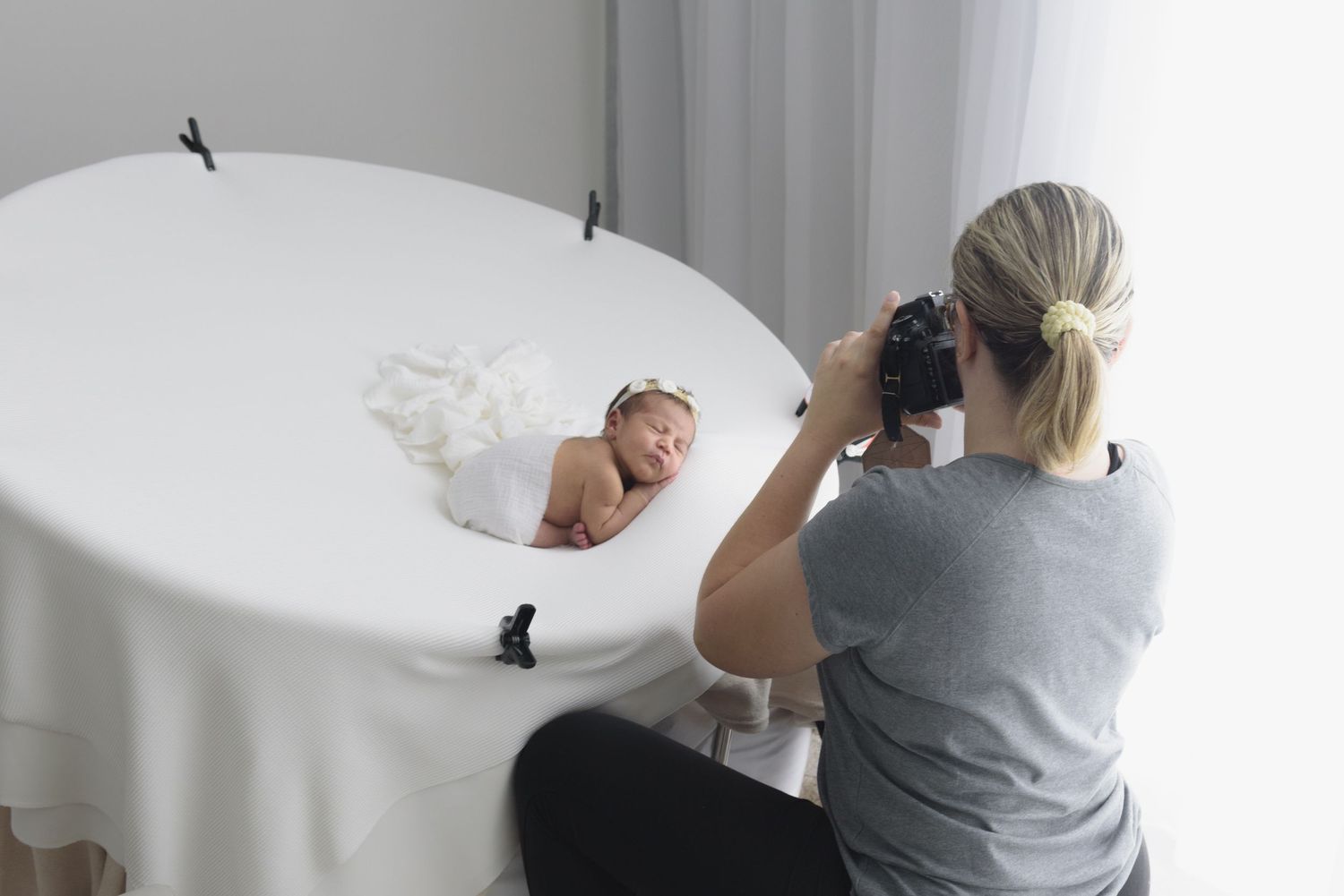 Professional photographers set up lighting equipment and adjust backdrops in a white studio space for a photoshoot – Paloma Schell