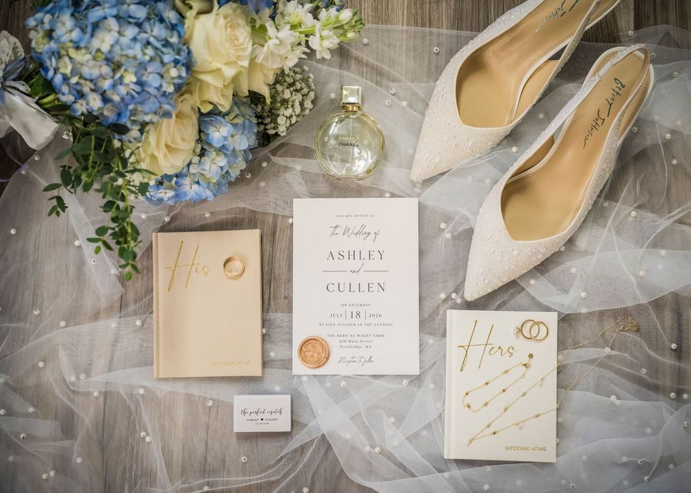 Wedding flat lay featuring invitation suite, heels, bouquet, and accessories in blue and ivory tones.
