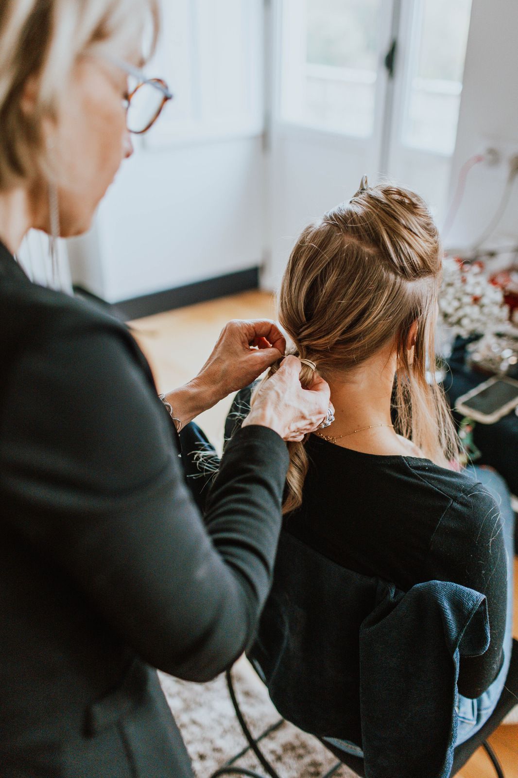 Hairstylist styling and pinning up client's hair in a professional salon setting.